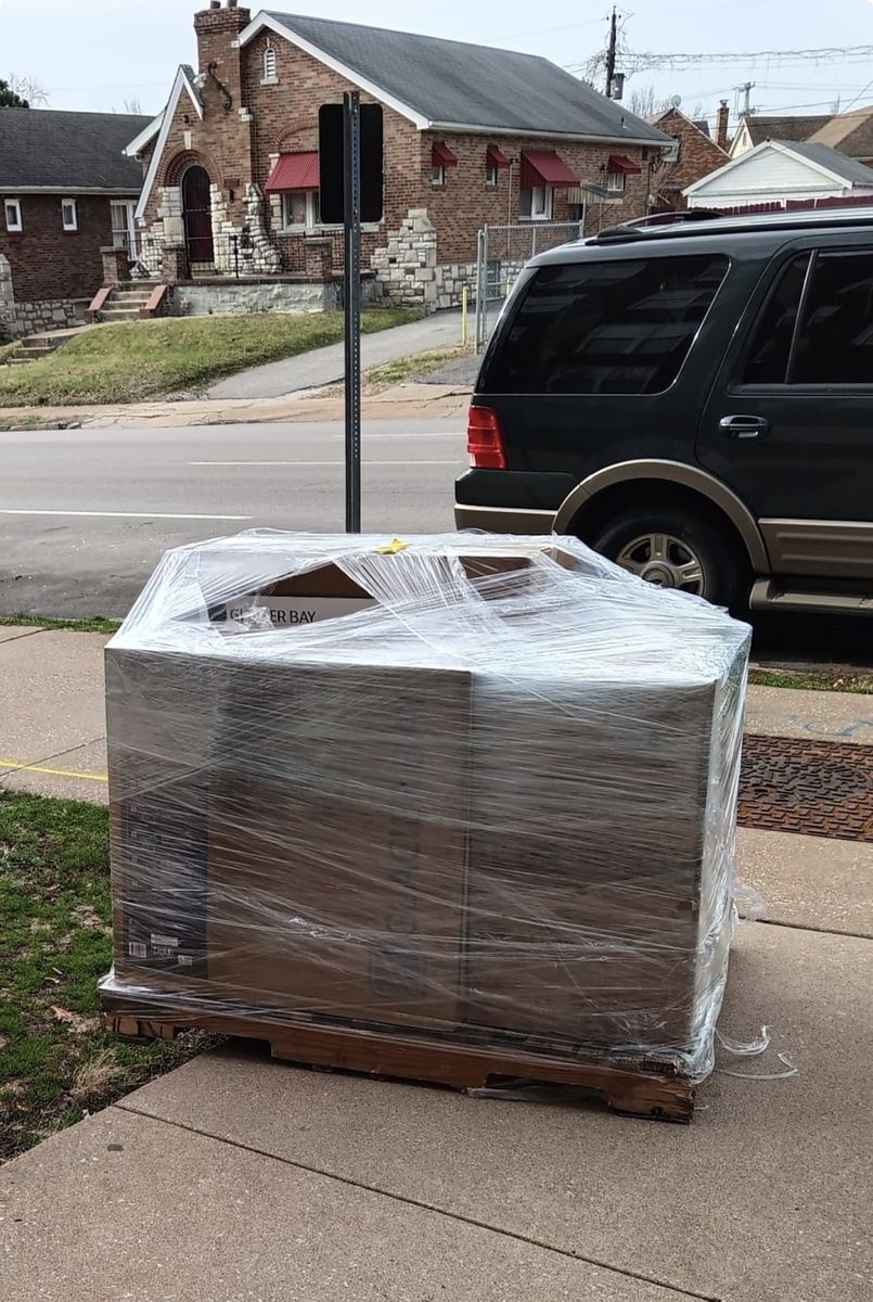 Large wrapped item on a pallet by a St. Louis brick home
